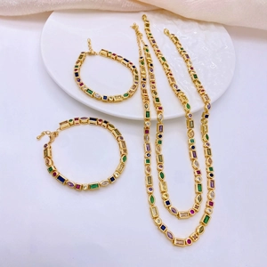 Minimalist gold necklaces and bracelets set with colorful geometric zircons on white fabric