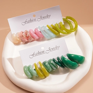 12-piece colorful geometric C-shaped acrylic hoop earrings set on white wavy tray