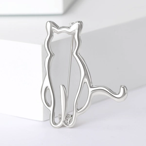 Close-up of minimalist silver cat brooch with hollow design on white geometric stand