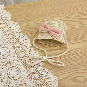 Detail of sweet straw crossbody bag with pink polka dot bow and white lace trim detail