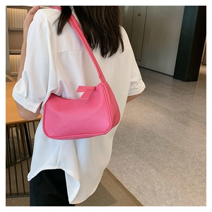 Detailed view of pink faux leather crescent underarm bag worn by a model in soft indoor light