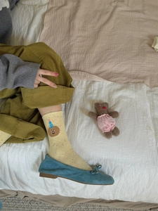 Detailed embroidery of a brown bear wearing a birthday hat on yellow cotton mid-tube socks