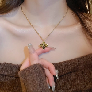 Detail of a gold clover pendant necklace with tiger eye stone worn on a female neck