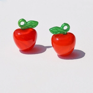Detailed view of red acrylic apple charms with green leaves for DIY jewelry making