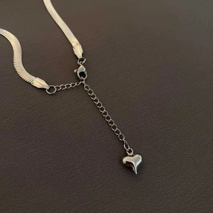 Detail of silver snake chain with lobster clasp and a delicate heart charm on the extender