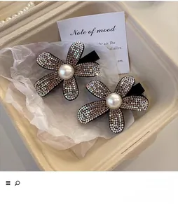 Detailed view of two luxury velvet flower hair claws with pearls and rhinestones in a gift box