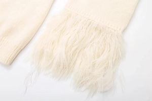 Detailansicht von cremefarbenem Strickstoff mit weichem Kunstpelzbesatz am Ärmel