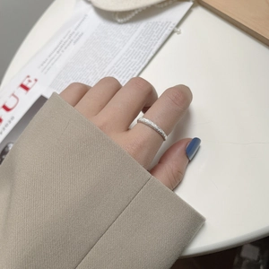 Detailed view of silver frosted ring with sparkling sand texture on finger
