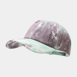 Detailed shot of tie-dye baseball cap featuring distressed edges and white embroidery