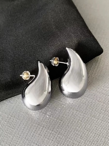 Macro detail of silver bean earrings with polished mirror finish and secure silicone backs