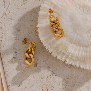 Macro detail of gold plated punk cuban chain stud earrings on white coral surface