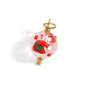 Macro detail of handmade Christmas glass bead pendant with red polka dots and golden bail