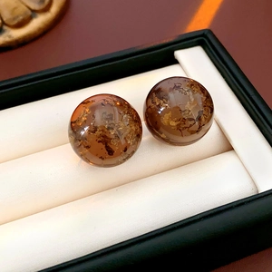Macro shot of amber resin ball earrings with gold foil details in a jewelry box