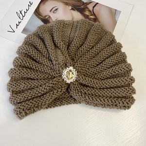 Detail of knitted turban hat with vintage rhinestone and pearl brooch decoration