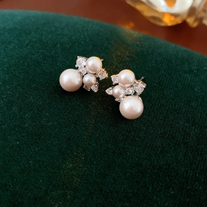 Detail of silver pearl and zircon earrings displayed on elegant dark green velvet