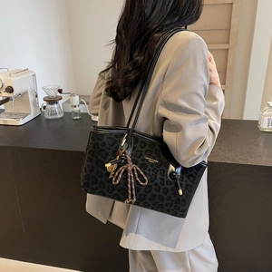 Large leopard print tote bag with bow detail worn by a model in a minimalist setting