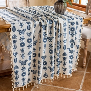Detailed view of blue floral cotton linen table runner with elegant beige fringe tassels