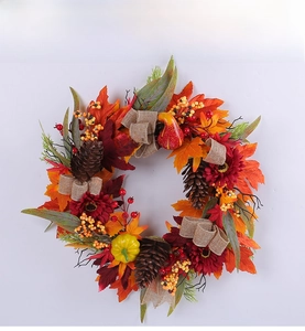 Detailed macro shot of an autumn wreath featuring red sunflowers, pinecones, and maple leaves