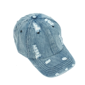 Détail macro de la casquette en jean vieilli montrant des trous et la texture du coton