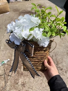 Detail of a woven cone door basket with white faux hydrangeas and a plaid bow decoration