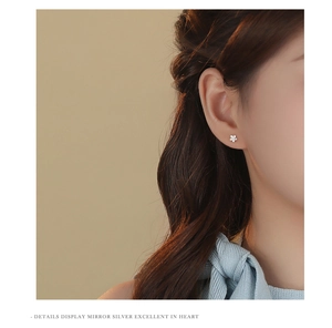 Close-up of elegant silver five-petal flower stud earring worn on a model ear