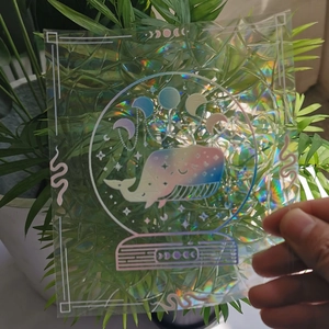 Close-up of holographic suncatcher sticker featuring a whale inside a crystal ball design