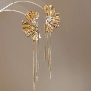 Detailed macro view of golden ginkgo leaf earrings with crystal studs and long tassels