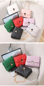 Various colors of quilted flap bags with gold chain straps displayed on a sofa