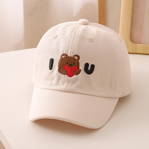 Dettaglio del ricamo dell'orso e delle lettere I U sul cappellino in cotone beige bimbo
