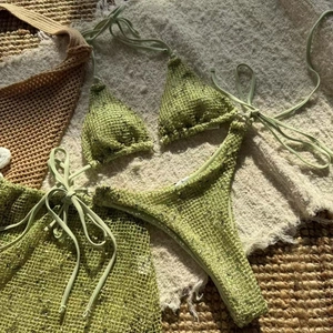 Close-up of green crochet three-piece bikini set with textured knit and metal ring detail