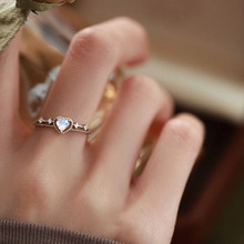 Macro detail of a heart-shaped opal stone set in a polished silver zircon ring band