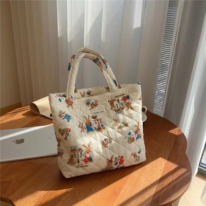 Detail of cream quilted tote bag with cute cartoon rabbit prints and simple wish label