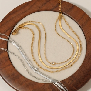 Multilayer stainless steel necklace with gold and silver chains in a wooden tray