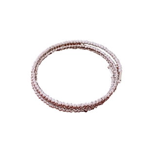 Minimalist twisted multilayer beaded bangle bracelet in metallic finish on white background