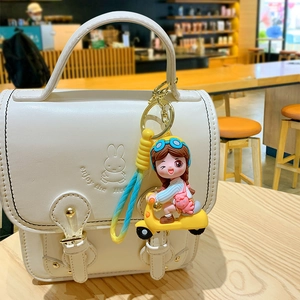 Cute cartoon girl on yellow scooter keychain with gradient strap on a white bag