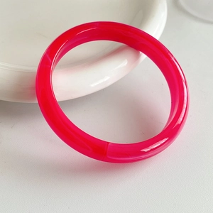 Close-up of translucent rose red resin bangle with smooth polished round edges