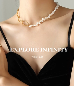 Close-up of asymmetric necklace featuring baroque pearls and gold oval chain links