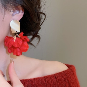 Close-up of model wearing luxury red petal flower tassel earrings with matte gold finish