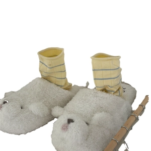 White plush animal slippers paired with yellow striped crew socks on a wooden sled base
