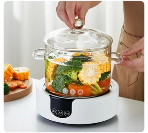 Close-up of hands lifting the lid off a glass pot containing fresh corn and broccoli
