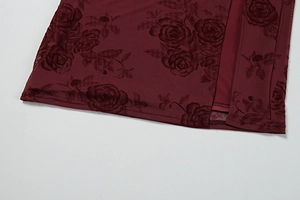 Detail of burgundy floral flocked mesh fabric with a high side slit on a summer dress