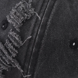 Macro view of distressed grey baseball cap with detailed embroidery and denim texture