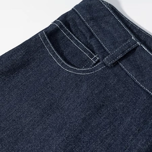 Gros plan sur la texture du denim bleu foncé et les surpiqûres blanches du jean