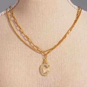 Detail of gold double-layered paperclip necklace with zircon letter C pendant