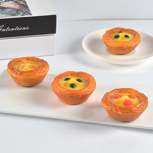 Set of four realistic artificial egg tarts with fruit toppings on a white tray