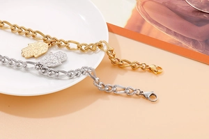 Dettaglio dei ciondoli mano di Fatima su bracciali a catena spessa in oro e argento