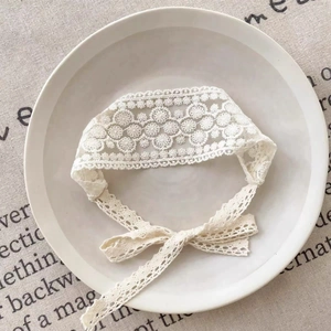 Vue détaillée d'un bandeau en dentelle blanche pour bébé avec rubans sur une assiette