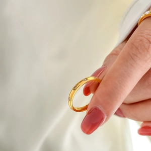 Close-up of gold ring band with round transparent diamonds and delicate minimalist design