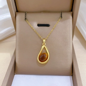 Macro detail of teardrop gold pendant with brown gemstone in a velvet jewelry box
