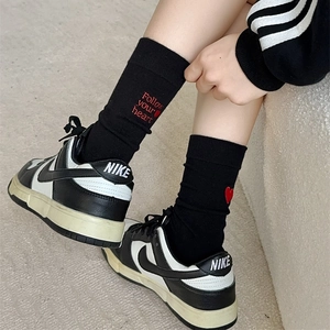Detail of black mid-calf socks featuring red heart embroidery and Follow your heart text